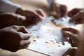 Close up members of multiracial team assembling white puzzle