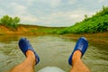 Close-up of men`s feet in rubber sandals on a catamaran on the background of the river, outdoor activities Royalty Free Stock Photo