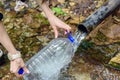 Close-up of men`s hands with a plastic bottle, fills with clean fresh water from the spring, underground source