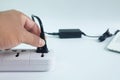 Close up men`s hands are Plug in Adapter power cord charger with blurred laptop computer on white Royalty Free Stock Photo