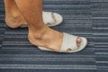 Men wear too tight sandal on his feet in the house