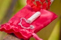 Close up of a a menstruation cotton tampon over a red cotton bag, with a beautiful red flower, in a blurred background Royalty Free Stock Photo