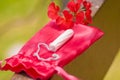Close up of a a menstruation cotton tampon over a red cotton bag, with a beautiful red flower, in a blurred background Royalty Free Stock Photo
