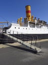 Close-up of merchant ship gangway with original yellow and red funnel or chimney under deep blue sky. Side view of deck and