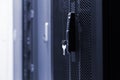 Close up meshed door with key in lock. Button in server room. Blur background of racks rows with network and hardware in the data