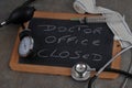 Doctor office closed written on a school slate surrounded by medical instruments