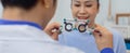 Close up messbrille eye test glasses in a hand of optometrist with blur women background. Checking eye vision by optician health