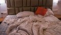 An empty rumpled bed in the hotel. Crumpled blanket and pillows. Close-up of messy bed. Used linens, bed sheet and