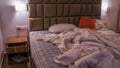 An empty rumpled bed in the hotel. Crumpled blanket and pillows. Close-up of messy bed. Used linens, bed sheet and