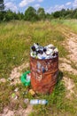 Close-up of a metal barrel with trash on the background of pristine nature. Pollution of