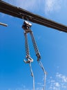 Close-up of a metal chain of a crane lifted up against a clear blue sky at a construction site in working condition for lifting