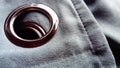 Close-up of a metal eyelet on a gray-blue curtain made of thick velvety fabric