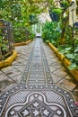 Close up of metal grating on tile walkway inside conservatory with plants on sides of walkway