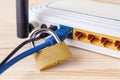 Close-up of metal padlock locked blue network cable of white Wi-Fi wireless router on a white wooden  table. Forbidden internet Royalty Free Stock Photo