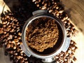 Close up of metal portafilter filled with coffee powder and coffee beans around on wooden table Royalty Free Stock Photo