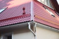 A close-up of a metal roof corner problem area with a roof gutter system that has two downspouts connected in one downpipe, a Royalty Free Stock Photo