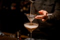 close-up on sieve through which male bartender pours frothy espresso martini cocktail into glass Royalty Free Stock Photo