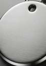 A close-up of a metallic circular object with a brushed texture, featuring a small hole Royalty Free Stock Photo