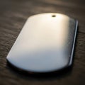 A close-up of a metallic dog tag lies on a textured wooden surface. The tag is rectangular with Royalty Free Stock Photo