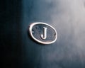 Close-up of a metallic letter 'J' on a dark background