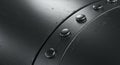 Close-up of a metallic surface with a curved seam and evenly spaced round rivets. Royalty Free Stock Photo