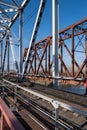 Close-up of the metalwork of a railway bridge over a river with a permitted pedestrian crossing