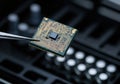Close-up of a microchip held with tweezers, showcasing intricate circuitry