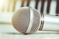 Close up on a microphone during recording session with a singer, piano in the background, music studio.