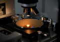 Close-up of a microscope examining a semiconductor wafer in a lab setting