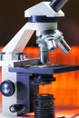 Close up of microscope lenses focused on a specimen in warm orange light light.