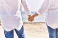 Close up of middle age hispanic couple of husband and wife together holding hands by the beach on a sunny day Royalty Free Stock Photo