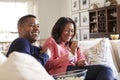 Close up of middle aged couple sitting on the sofa in their living room watching TV, laughing and eating popcorn, close up Royalty Free Stock Photo