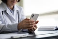 Close up middle aged female doctor using cellphone. Royalty Free Stock Photo