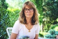 Close-up of middle aged woman wearing glasses and white shirt while relaxing on the patio at home Royalty Free Stock Photo