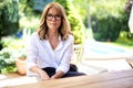 Close-up of middle aged woman wearing glasses and white shirt while relaxing on the patio at home Royalty Free Stock Photo