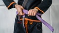 Close up on midsection of unknown bjj brazilian jiu jitsu athlete tie up purple belt on the kimono gi uniform at the academy