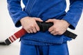 Close up on midsection of unknown caucasian male athlete bjj brazilian jiu-jitsu black belt standing on the mat at academy holding