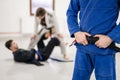 Close up on midsection of unknown caucasian male athlete bjj brazilian jiu-jitsu black belt standing on the mat at academy holding