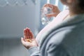Close up on midsection of unknown caucasian woman pregnant mother holding medicine supplement drugs and glass of water - taking Royalty Free Stock Photo