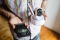 Close up on midsection of unknown man holding home security surveillance camera and mobile phone trying to install an app top view Royalty Free Stock Photo