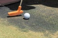 Close up of a miniature or mini golf ball and orange putter on artificial grass outdoors with copy space Royalty Free Stock Photo