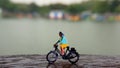 Close up Mini Figure Woman toys bicycling at River Side Path Way with negative or copy space for text area placement