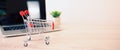 Close up the mini shopping cart and laptop at desk concept using the internet application for online shopping Royalty Free Stock Photo