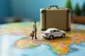 Close up Miniature businessman, suitcase, handbag, and white car amid a vibrant world map