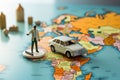 Close up Miniature businessman, suitcase, handbag, and white car amid a vibrant world map