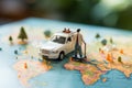 Close up Miniature businessman, suitcase, handbag, and white car amid a vibrant world map