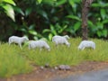 a close up of miniature figures of a herd of goats eating grass.
