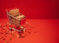 Close up of miniature shopping cart with craftpaper gift on a red background