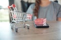 Close up of miniature shopping cart /trolley toy figure. smart phone and red gift box on table for shopping and e-commerce concept Royalty Free Stock Photo