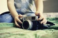 Close up of a mirrorless retro camera on the bed. Little girl playing with camera. Talented little girl has fun with vintage